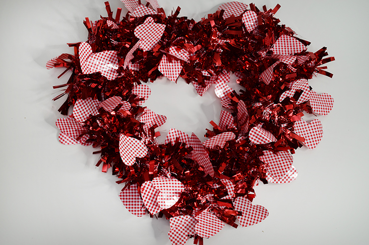 Wreath in a heart shape with Valentine's Day garland that has red ruffles and red and white hearts. 