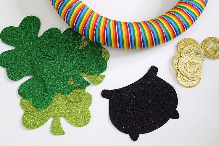 Supplies for St. Patrick's Day rainbow wreath, including rainbow ribbon, black pot and green shamrocks decals and gold coins.