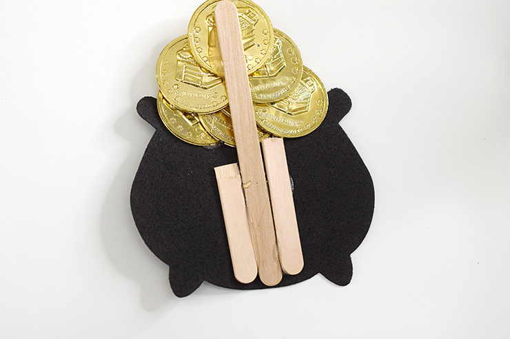 Attach gold coins and black cauldron to a popsicle stick to hot glue to the wreath.