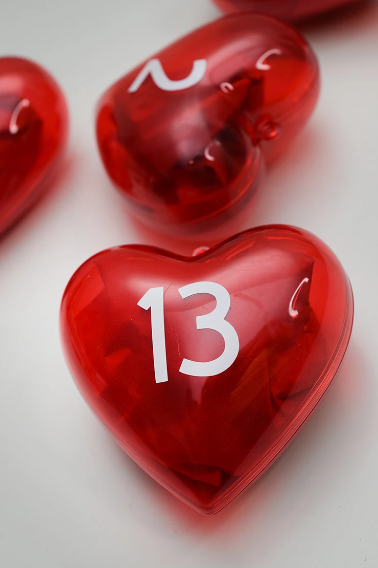 Red, heart-shaped ornament with candy inside and the number 13 on the outside.